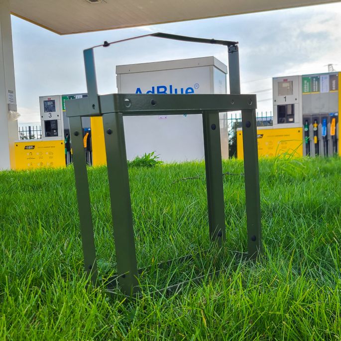 Groene jerrycanhouder groen in het gras voor tankstation